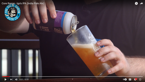 A man pours a delicious craft beer into a chilled glass that has condensation on it 